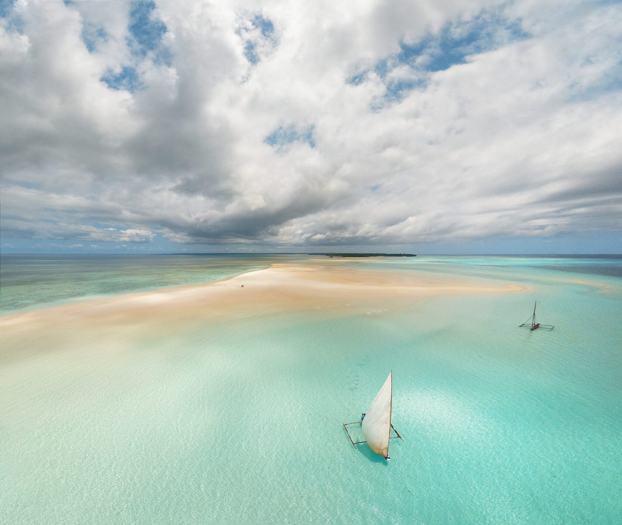 Luftaufnahme einer Sandbank vor Pemba Island, zwei Ngalawa-Segelboote liegen im türkisen Wasser