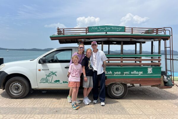 Familie vor dem offenen Transferwagen des Resorts